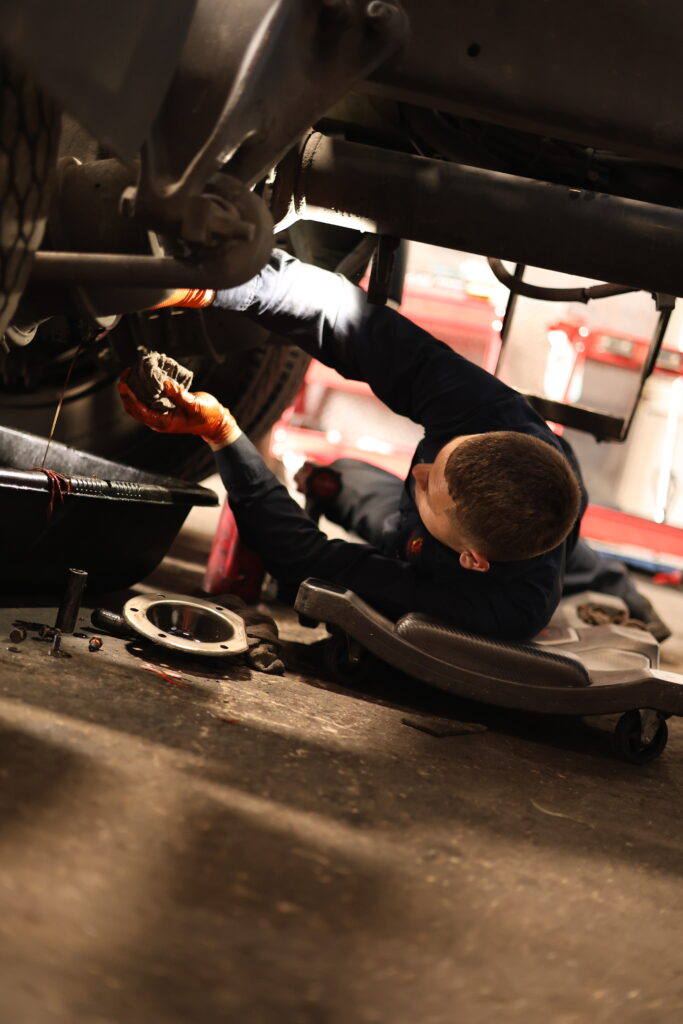 Mechanic inspecting components beneath a truck
