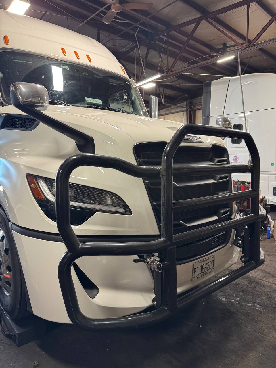 Close view of a black deer guard fitted to a white Freightliner semi-truck