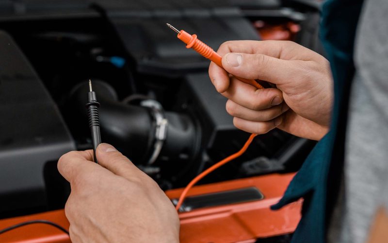 cropped-shot-of-auto-mechanic-with-multimeter-volts-75JAMKL.jpg